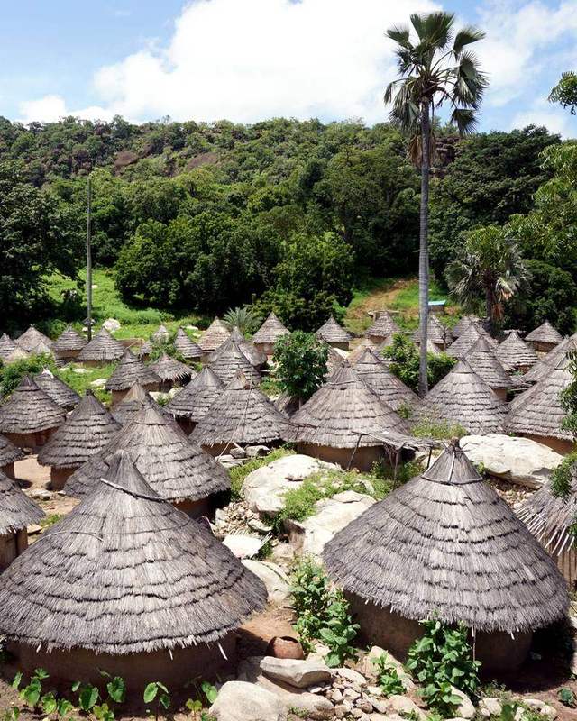 Casas tradicionales de techo cónico de paja en el pueblo de Iwol, entre árboles y rocas